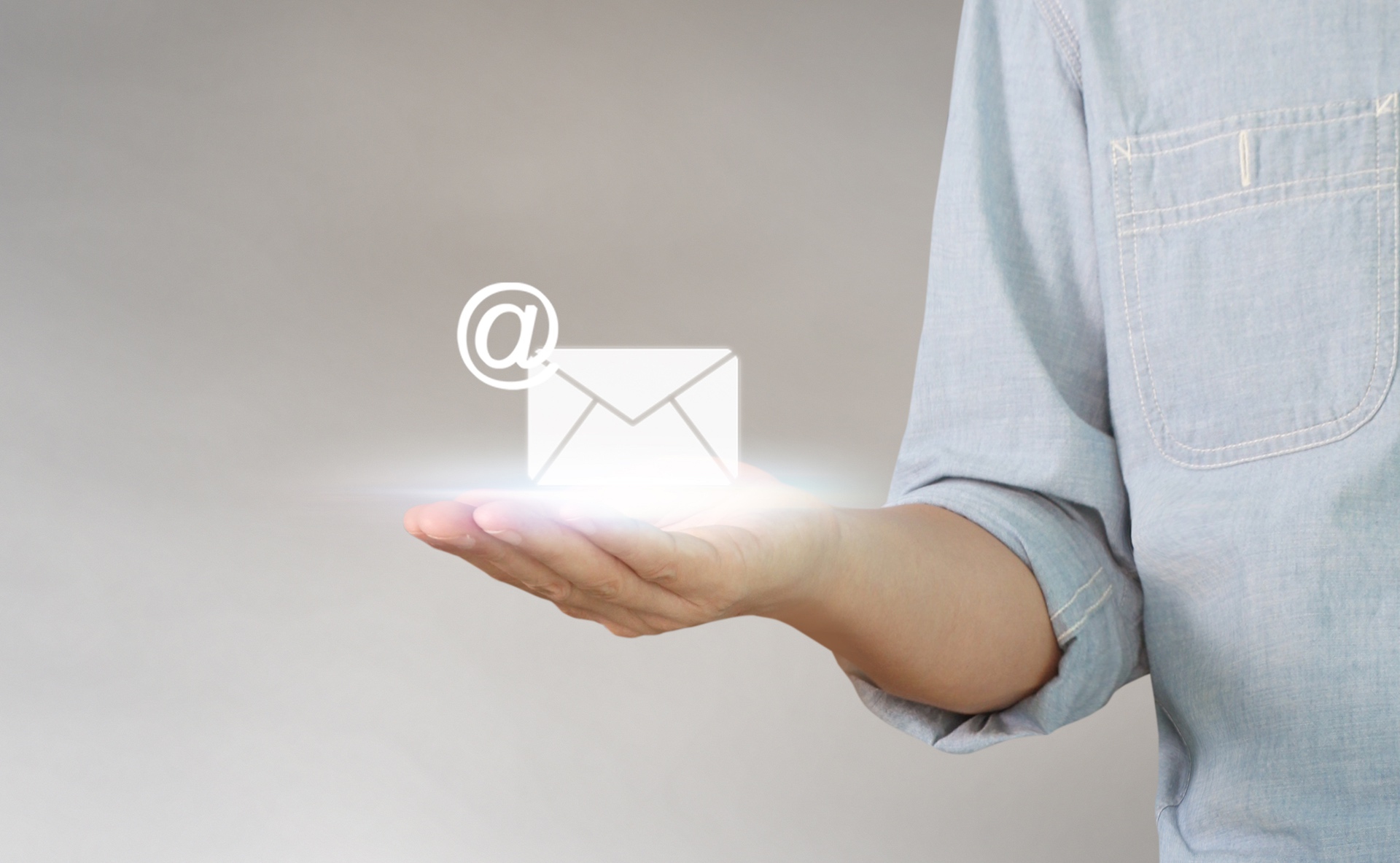 glowing icon of envelope and @ sign in the palm of a hand